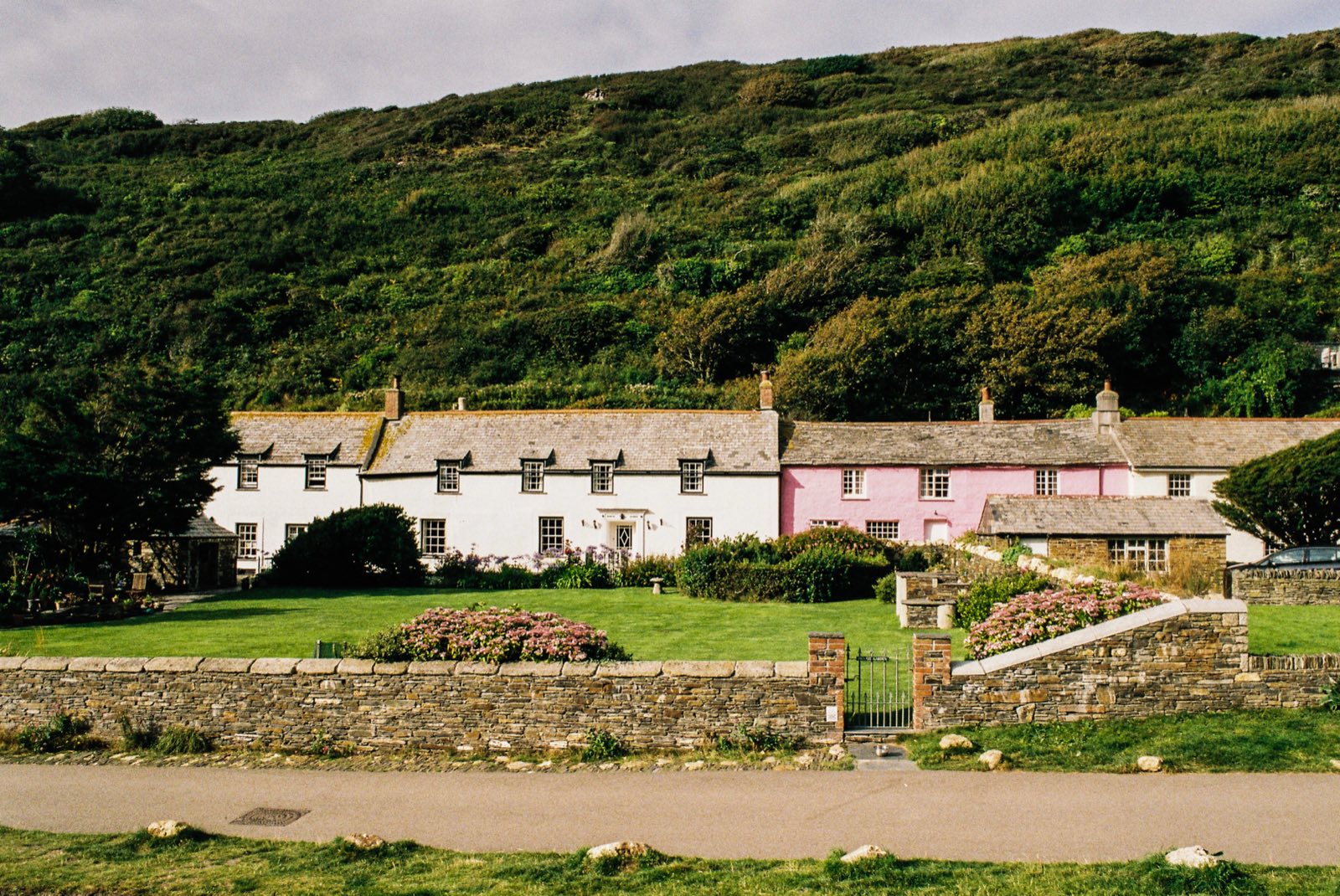 Row of Cornish cottages beneath a green hillside